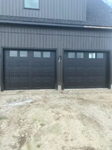 Two new black garage doors with windows installed on a modern home by Hickman Overhead Door in Milford, DE.