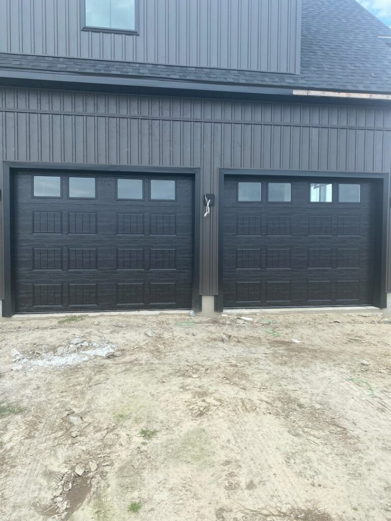 Two new black garage doors with windows installed on a modern home by Hickman Overhead Door in Milford, DE.