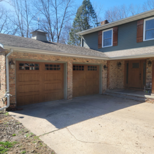 Two newly installed brown garage doors on a brick house by 74 Garage Door Company in Lake Park, FL