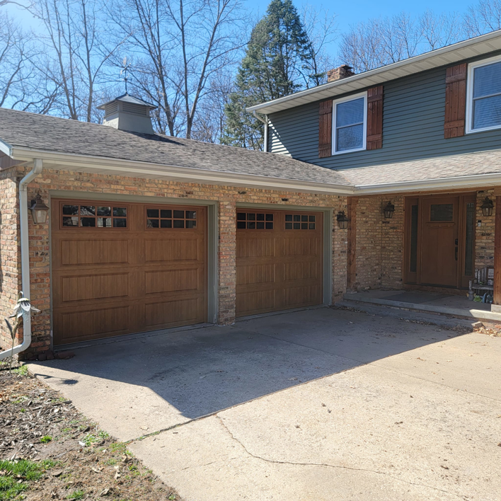 Two newly installed brown garage doors on a brick house by 74 Garage Door Company in Lake Park, FL