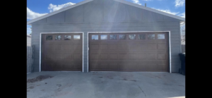 Two newly installed brown garage doors on a residential property by PS Garage Doors of Williston, ND.