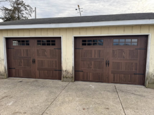 Two newly installed brown wood-grain garage doors with windows and decorative hardware by Bailey Garage Doors MT in Belgrade, MT.
