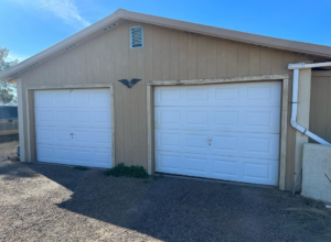 Two new white garage doors installed on a residential property by Espada Garage Door and Gate, LLC in Las Cruces, NM.
