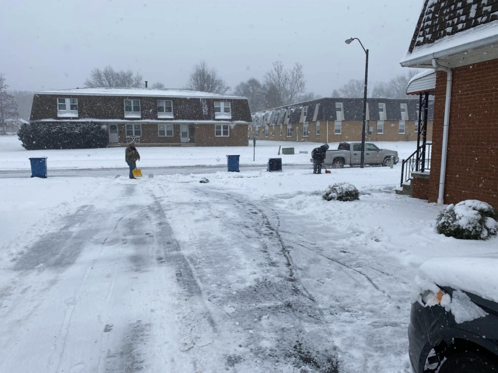 Two team members diligently shoveling snow from a residential driveway, offering snow removal by Limitless Home And Lawn Renovations in Youngstown, OH.
