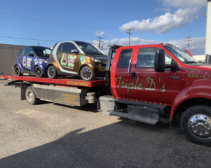 Two Smart cars being transported on a flatbed tow truck by Triple D's Towing in Sterling Heights, MI.