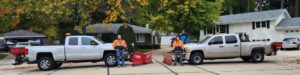 Two snow plow trucks with salt spreaders and crew members, ready for snow removal services from JCO Landscape & SNOW in Racine, WI.