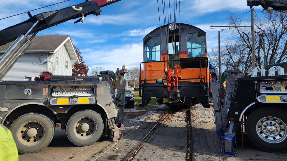 Two Elmquist Towing & Recovery trucks lifting a train locomotive off the tracks in Ames, IA.