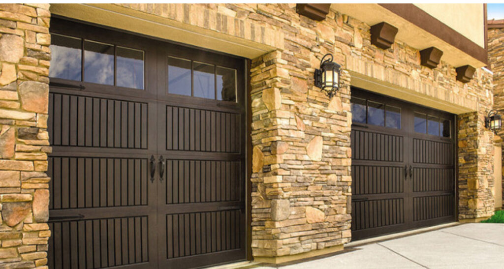 Two traditional brown garage doors with decorative windows on a stone house by Total Garage Solutions in Kalispell, MT.