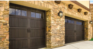 Two traditional brown garage doors with decorative windows on a stone house by Total Garage Solutions in Kalispell, MT.