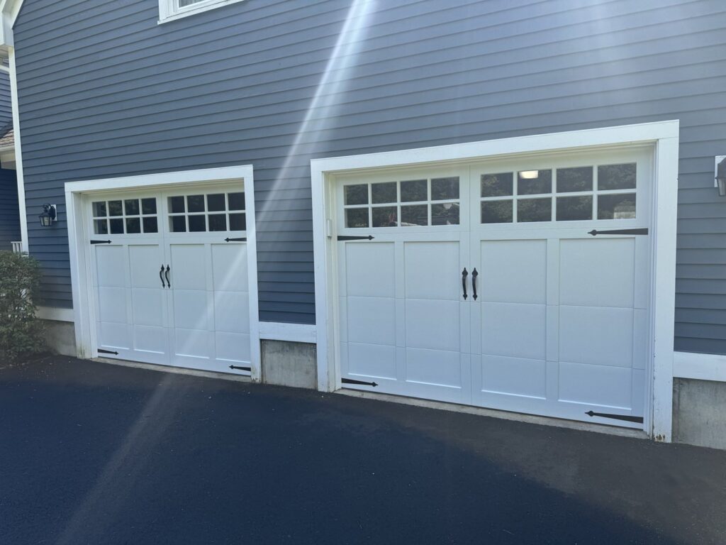 Two white carriage-style garage doors with windows and black hardware installed by J.A. Overhead Door in Westfield, MA.