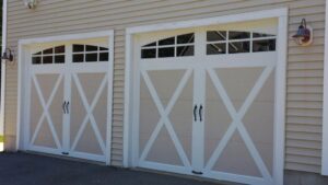 Two white carriage-style garage doors with X-bracing and decorative handles, installed by Steve Shumsky Unlimited Overhead Doors LLC in Hudson, NH