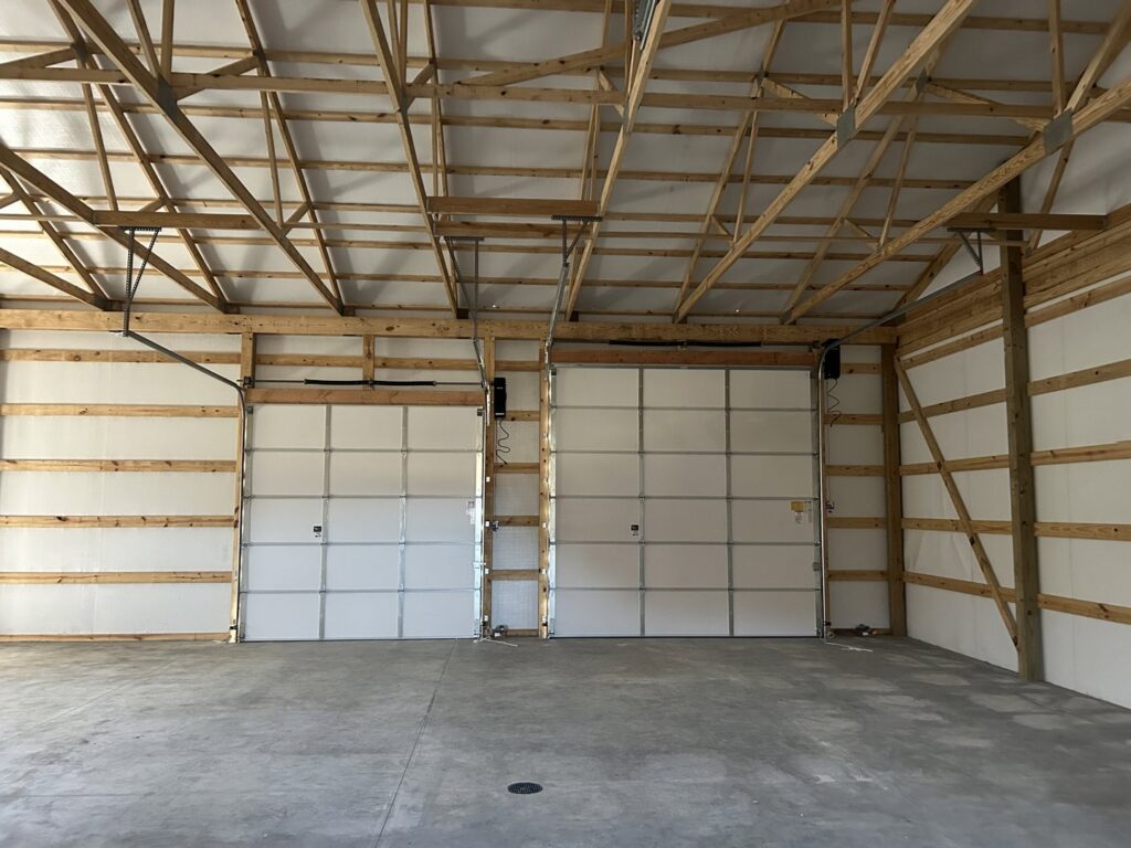 Two white garage doors installed inside a large commercial or agricultural building by Woodwards Overhead Door Co. in Topeka, KS