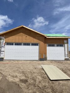 Two white garage doors with windows installed on a house under construction by Apex Garage Doors in Columbus, OH.