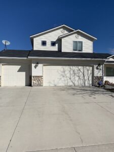 Two white garage doors with windows installed on a residential house by Overhead Door Company of Nampa in Nampa, ID.