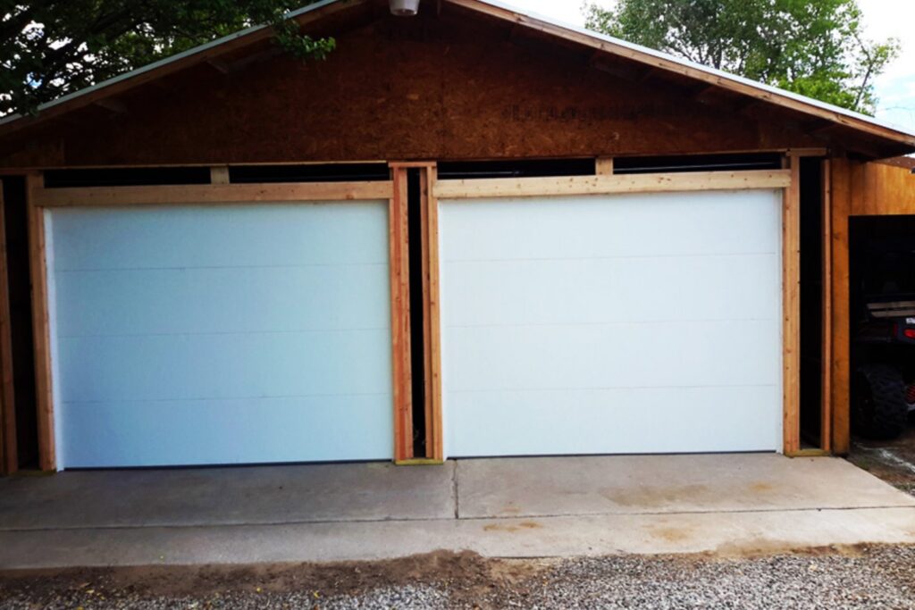 Two white garage doors being installed on a new garage structure by Mark's Garage Door Services in Santa Fe, NM.
