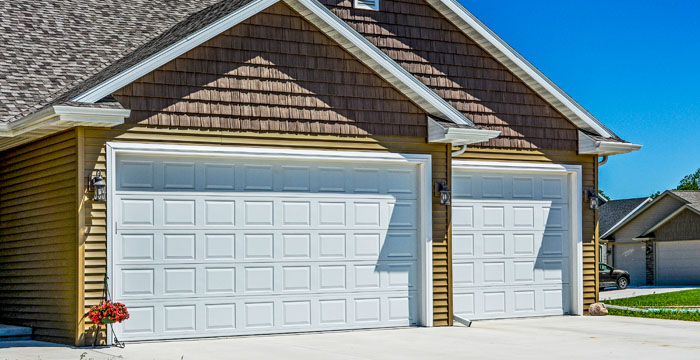 Two newly installed white panel garage doors on a residential home by AMR Distribution Center in Wichita, KS