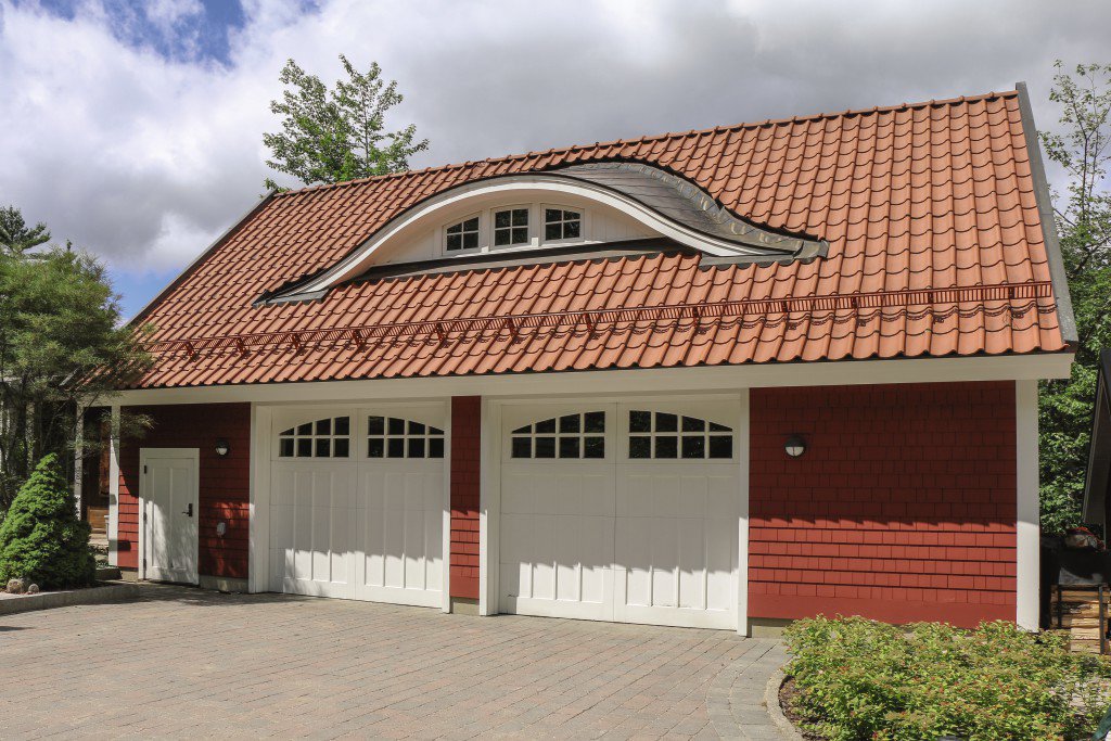 A red-sided house with two white panel garage doors, installed by Overhead Door Co of Missoula in Missoula, MT.