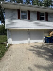 Two newly installed white panel garage doors on a white residential home by The Door Pros in Wichita, KS