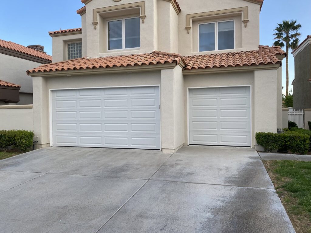 Two newly installed white paneled garage doors on a residential home by Legacy ODS Garage Door Services in Las Vegas, NV.