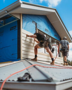 Two skilled workers installing siding on the gable end of a house, a typical job for Ideal Siding Nashville, TN.