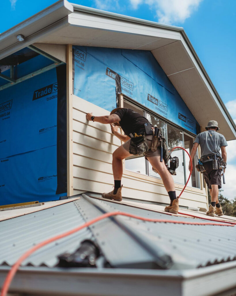 Two skilled workers installing siding on the gable end of a house, a typical job for Ideal Siding Nashville, TN.