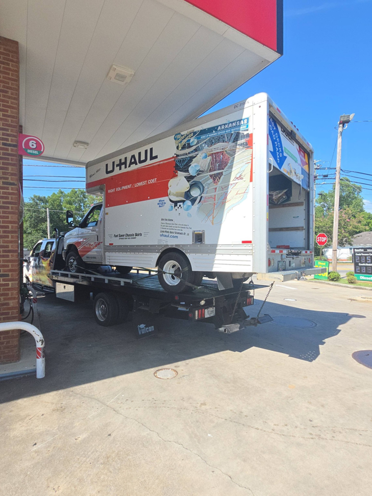 A U-Haul box truck being transported on a flatbed tow truck by Dees Custom Auto in Newnan, GA.