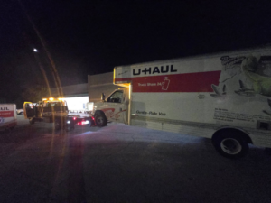 A U-Haul truck being loaded onto a flatbed tow truck at night by Dees Custom Auto in Newnan, GA.