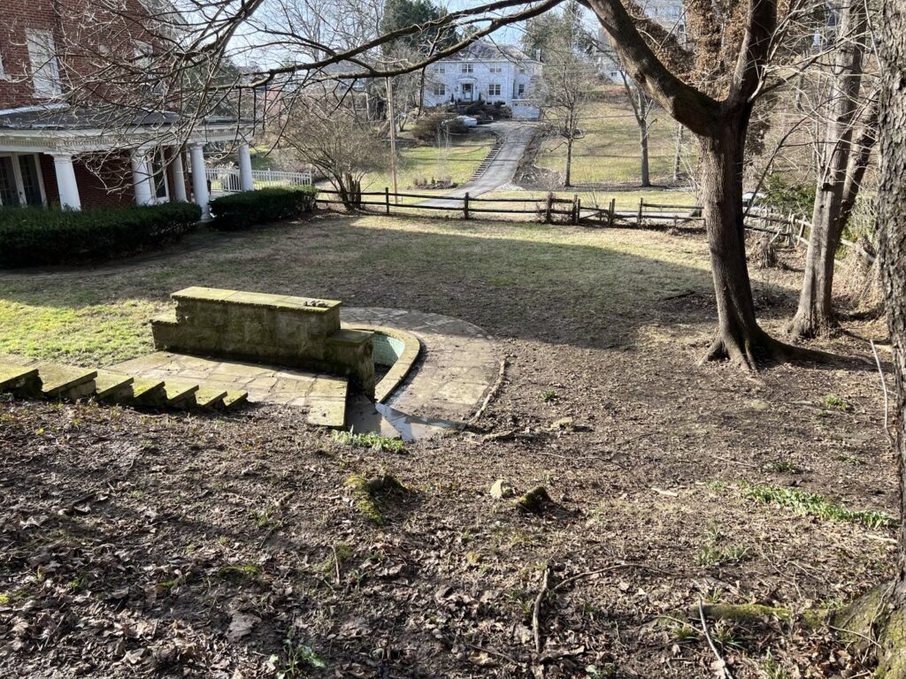 An unkempt yard with bare ground and a stone structure, indicating a need for professional cleanup from Ripley's Lawn Care, LLC in Charleston, WV.