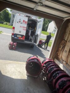 PuroClean technicians unloading water damage drying equipment from a van at a job site in Lancaster, PA.