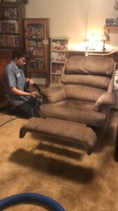 A technician from Pile's Carpet Care & Restoration Service cleaning an upholstered recliner in Elizabethtown, KY.