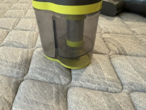 A vacuum cleaner dustbin on a quilted surface, showing cleaning work by Danielle's cleaning service in Xenia, OH