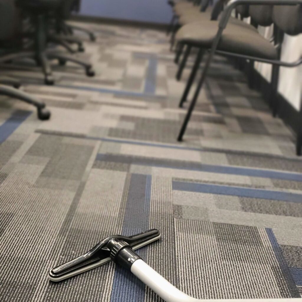 A vacuum cleaner head on a patterned carpet, ready for cleaning by Rubber Gloves Residential Cleaning in San Antonio, TX.