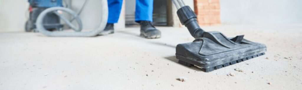 A person vacuuming a dusty floor, demonstrating thorough cleaning services by Orange Cleaning Services in Stamford, CT.