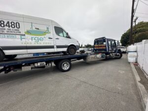 An Affordable Towing LLC flatbed tow truck transporting a white van in Anaheim, CA.