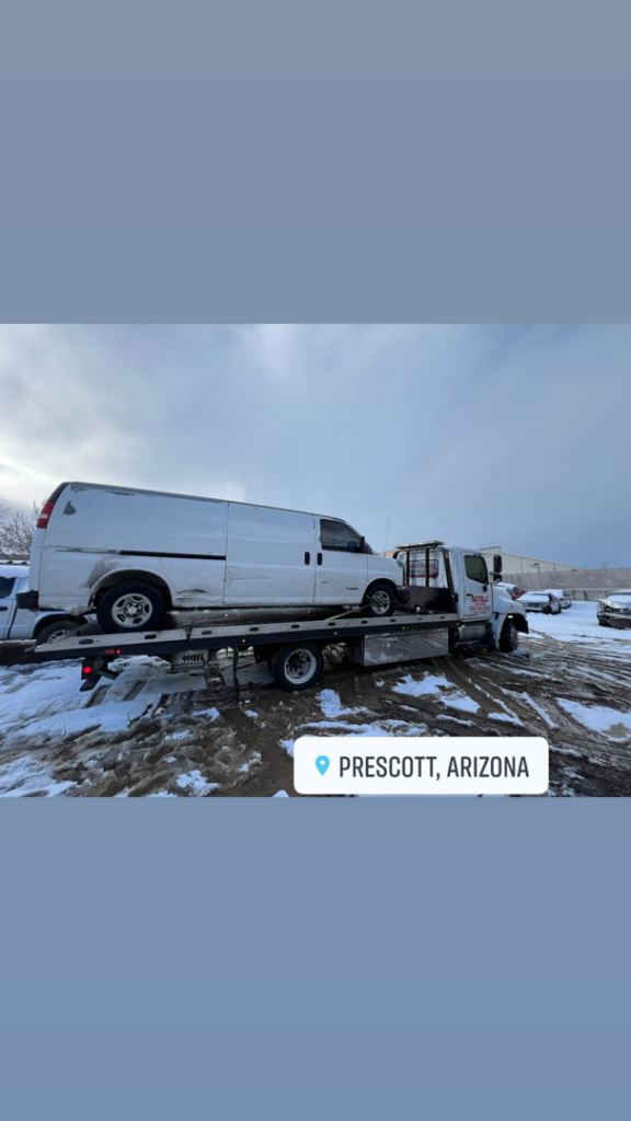 Sotelo Towing LLC providing flatbed towing for a white van in snowy conditions in Phoenix, AZ.