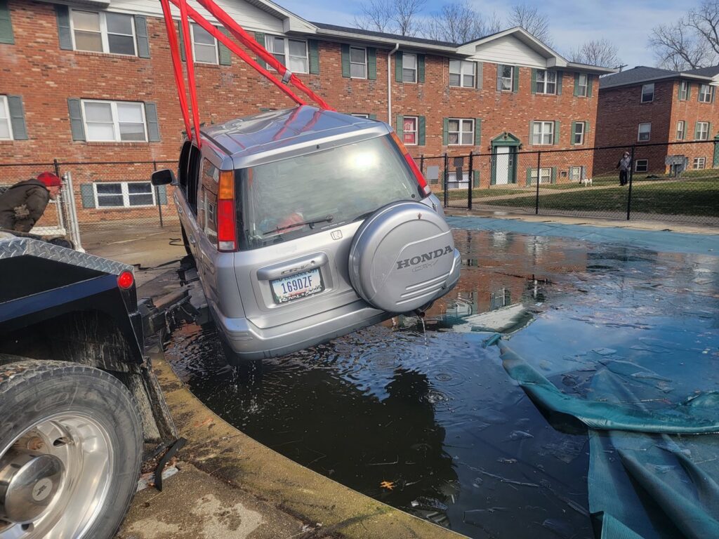 A TowTime Towing and Recovery team recovering a silver Honda CRV from a swimming pool in Bloomington, IN.