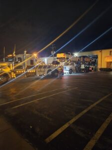 A McDowell Wrecker Service tow truck with a car carrier trailer loaded with vehicles at night in Springfield, MO.