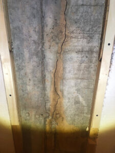 A vertical foundation crack visible on a concrete wall, a common issue addressed by Northeast Wisconsin Waterproofing, LLC in Green Bay, WI.