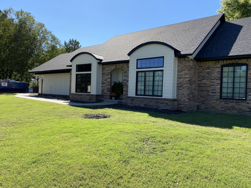 A residential home featuring a combination of brick and stylish white vertical siding by Xtreme Exteriors in Rogers, AR.