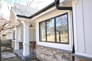 Vertical white siding and stone accent detail on a home's exterior by Ideal Siding Dallas, TX.