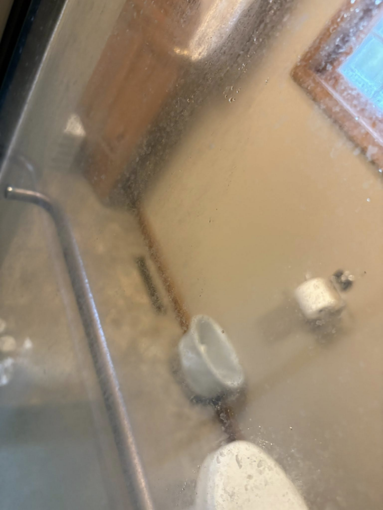 A very dirty shower door covered in grime and water spots, needing cleaning by Danielle's cleaning service in Xenia, OH