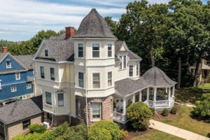 A grand Victorian-style house with new yellow siding and white trim by United Home Experts in Ashland, MA.