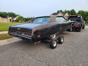 A vintage black car being towed with dollies by Nacho Transports llc in Middletown, DE.