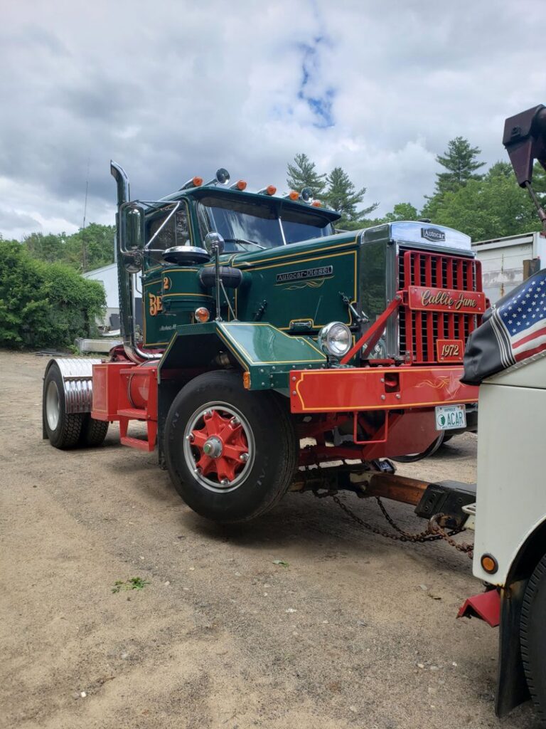 A vintage green and red wrecker tow truck from Bailey's Towing and Auto Body, LLC, ready for service in Merrimack, NH.