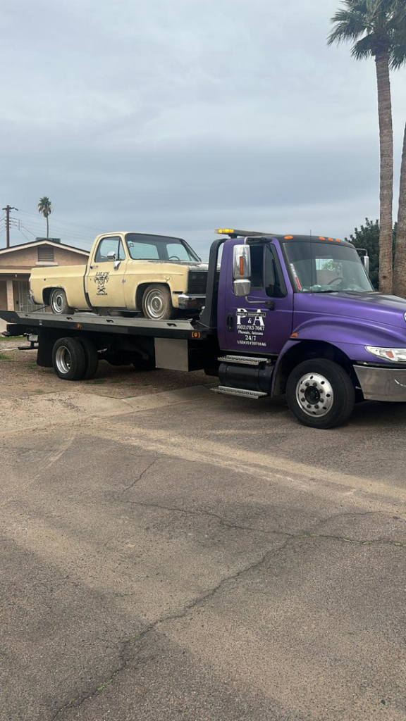 A vintage cream-colored pickup truck being towed on a flatbed tow truck by P&A towing & transport Llc in Phoenix, AZ