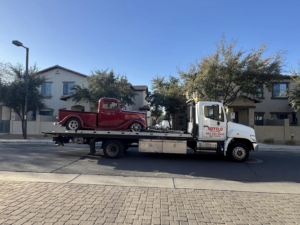 Sotelo Towing LLC transporting a classic red vintage truck on a flatbed tow truck in Phoenix, AZ.