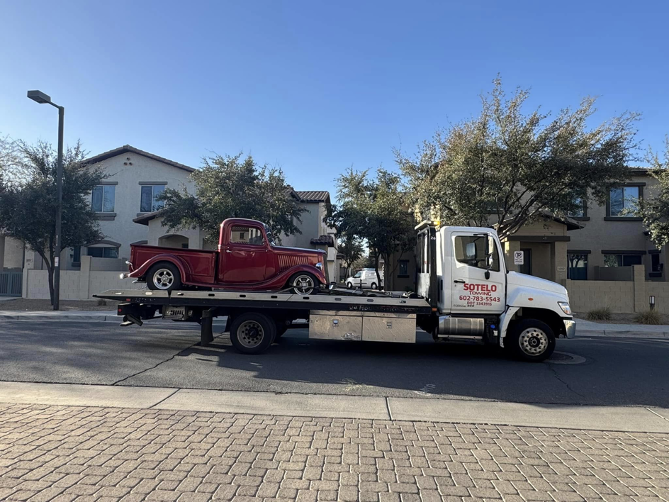 Sotelo Towing LLC transporting a classic red vintage truck on a flatbed tow truck in Phoenix, AZ.