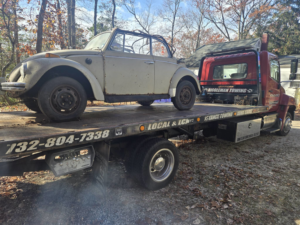 A vintage Volkswagen Beetle convertible being towed on a flatbed truck by Riggleman Towing in Moorefield, WV.