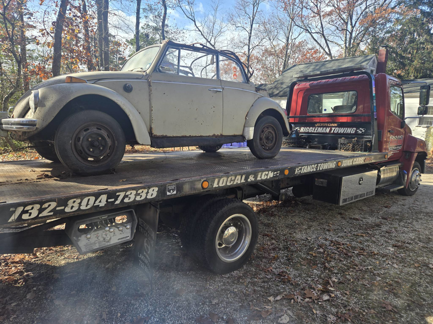 A vintage Volkswagen Beetle convertible being towed on a flatbed truck by Riggleman Towing in Moorefield, WV.