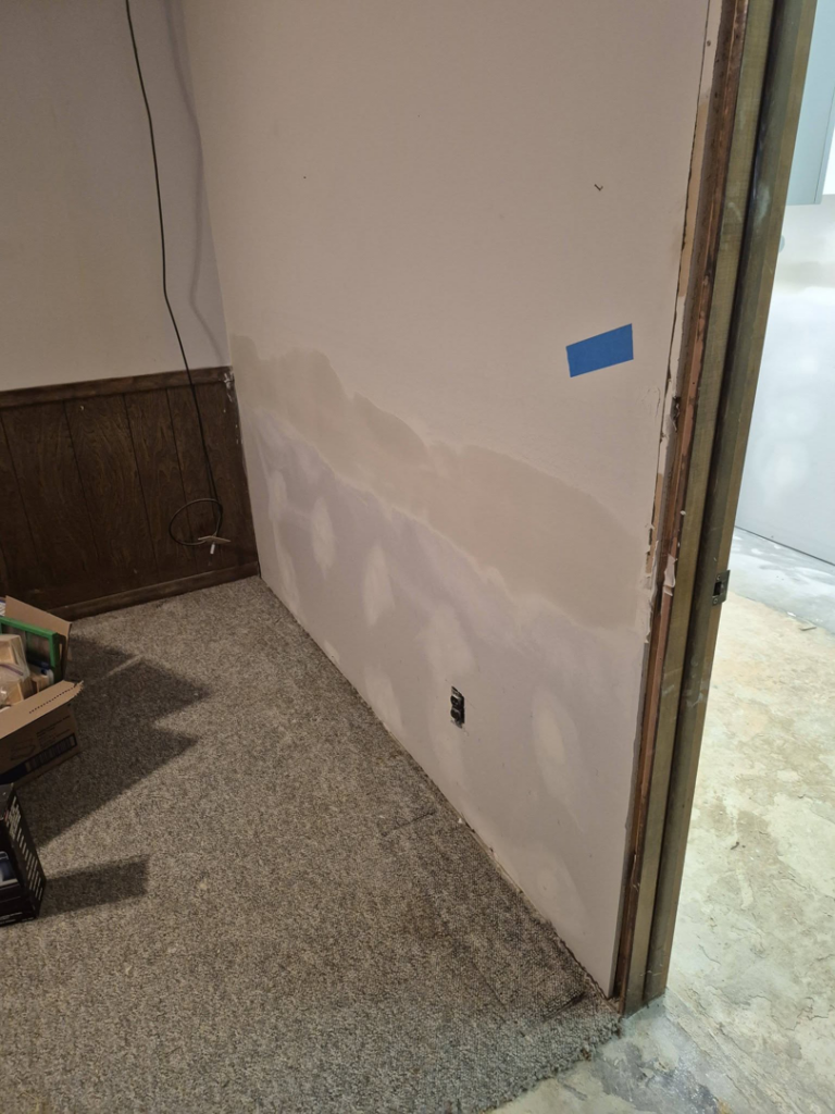 Water damage on wall with blue tape for assessment and repair by Risen Handyman services LLC, Council Bluffs, IA.